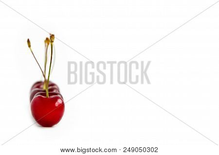 Ripe Red Cherries Are Lined Up, One After The Other. One Cherry In Focus On White Background