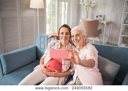Memorable Photo. Two Beaming Women Making Memorable Photo While Sitting On Comfortable Sofa At Home 
