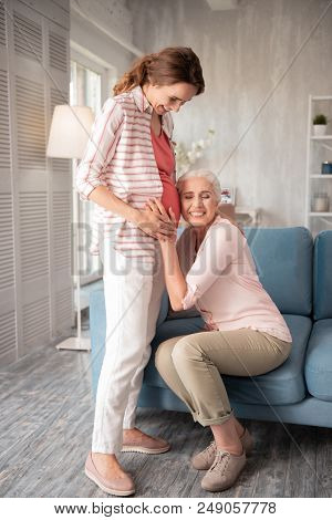 Happy Woman. Extremely Happy Woman Feeling So Excited And Delightful While Placing Her Ear Near Preg
