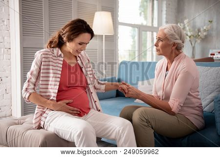 Needed Support. Grey-haired Mother Feeling Concerned While Supporting Her Pregnant Daughter Sufferin