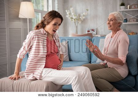 Surprised Moves. Dark-haired Pregnant Woman Feeling Extremely Surprised While Feeling Moves Of Littl