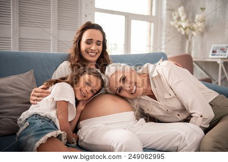 Laughing Woman. Pregnant Beautiful Stylish Woman Laughing While Sitting On Sofa Near Her Loving Fami