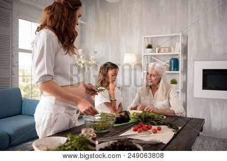 Pregnant Housewife. Pregnant Appealing Housewife Cooking Healthy Vegetable Salad For Her Mother And 