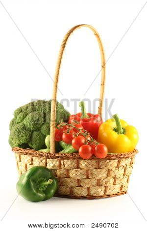 Brokolice, paprika, okurky a rajčata v košíku na bílém pozadí.