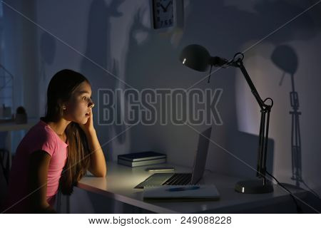 Upset teenage girl with laptop in dark room. Cyber bullying