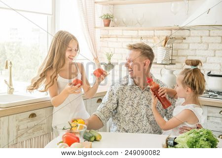 dad with two little daughters have a fun in the kitchen