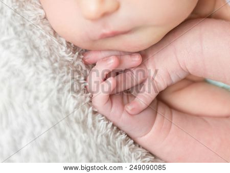 Close-up of newborn tiny hands. Child hands close-up. Little baby hands on white blanket