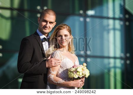 Tender Fiance And Fiancee On Their Wedding Day Standing Near Futuristic Modern Building With Big Win