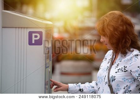 Woman using parking meter in parking zone area in a city