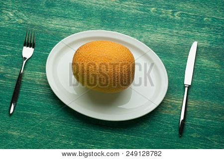 Yellow Melon Fruit On Plate With Cutlery. Top View .