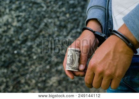 Arrested Hispanic Man In Handcuffs With Dollar Banknote. Arrested For Attempting To Bribe. Concept O