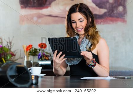 Young woman in a cafe or restaurant, she using her tablet computer for emails and video chat