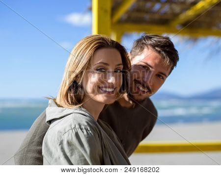 Happy couple enyojing time together on beach during autumn day