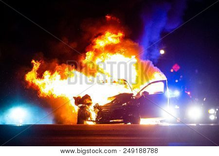 Car On Fire At Night With Police Lights In Background