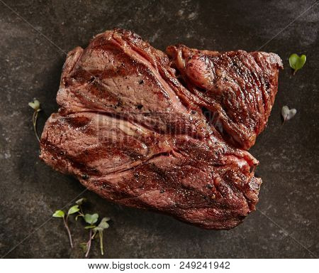 Hot Grilled Whole Alternative Steak on Black Stone Background. Fresh Juicy Medium Rare Beef Grillsteak. Barbecue Meat Top View Close Up