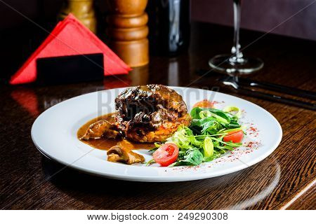 Meat Dish. Appetizing Beef Cheeks In Sauce With Tomatoes And Basil Leaves In A Restaurant