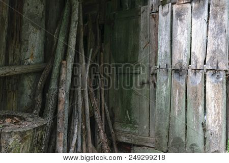 Old Rural Green Wooden Door And Dry Sticks Placed In The Barn Corner