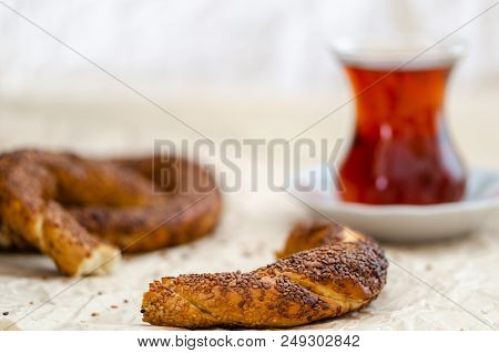 There Is Half Of The Simit In Front Place, While You Can See Whole Simit With Turkish Tea In The Bac