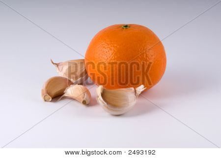 Segmente von Knoblauch und eine reife Orange auf hellem Hintergrund