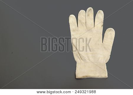 White Knitted Working Glove With Stretchable Cuff On The Dirty Gray Background. With Clipping Path