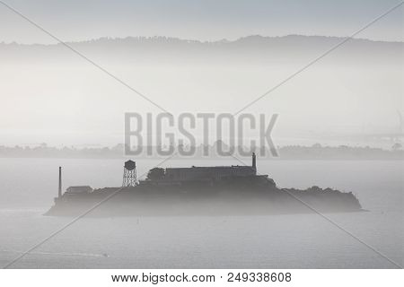 Alcatraz, In Infamous Prison Of An Island Of The Same Name Is Viewed From Afar In A Foggy San Franci