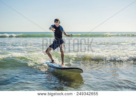 Young Man, Beginner Surfer Learns To Surf On A Sea Foam On The Bali Island.