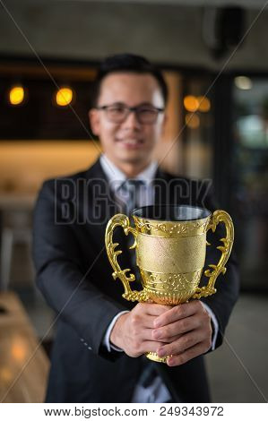 Asian Businessman Holding A Golden Trophy Cup To Cheerful And Celebrated His Successful In Career An