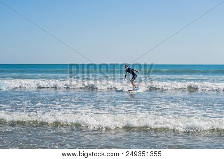 Young Man, Beginner Surfer Learns To Surf On A Sea Foam On The Bali Island.