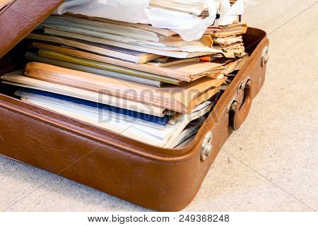 Old Fashioned Suitcase Made Of Leather Is Full Of Folders, Papers And Documents, Overloaded.