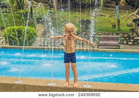 Happy Boy Playing With The Water Fountain In The Pool.