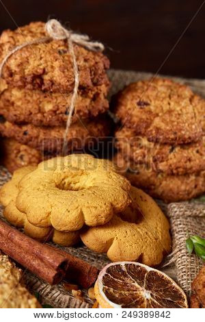 Conceptual Composition With Assortment Of Cookies, Cinnamon Sticks Bunch And Dried Oranges With Burl