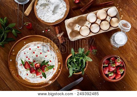 Top View Raw Ingredients For Cooking Strawberry Pie Or Cake On Wooden Table: Eggs, Flour, Sugar And 
