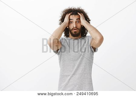 Worried Desperate Aduly Male Freelancer With Afro Haircut In Trendy Striped T-shirt, Holding Hands O