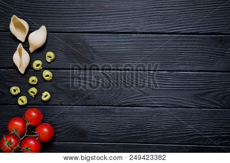 Pasta Conchiglie And Tortellini. Red Cherry Tomatoeson Black Background.  Italian Cuisine On Wooden 