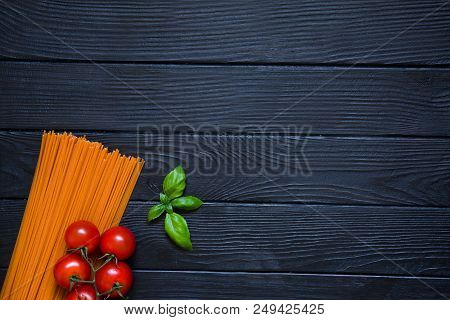 Tomato Spaghetti With Fresh Cherries And Basil Leaf On Black Wooden Table Background. Italian Cuisin