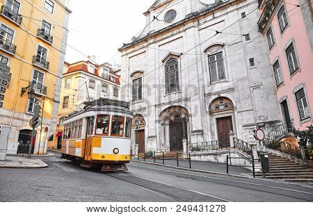 Lisbon, Portugal. Vintage yellow retro tram on narrow bystreet tramline in Alfama district of old town. Popular touristic attraction of Lisboa city.