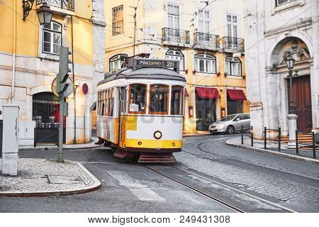 Lisbon, Portugal. Vintage yellow retro tram on narrow bystreet tramline in Alfama district of old town. Popular touristic attraction of Lisboa city.