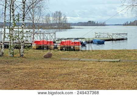 Pier, Pontoon On The Waterside Of The Lake Seliger With Catamarans And Boats With Forest On The Back