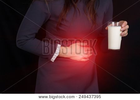The Girl On A Black Background Holds On To Her Stomach And Holds In Her Hand A Glass Of Milk, Heartb