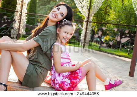 Beautiful Mother And Daughter Sitting Outdoors, Laughting And Having Fun. Concept Of Happy Family