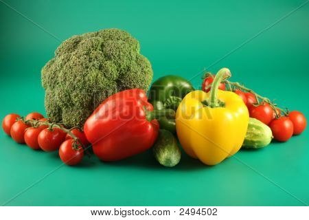 Brokolice, paprika, okurky a rajčata na zeleném pozadí.