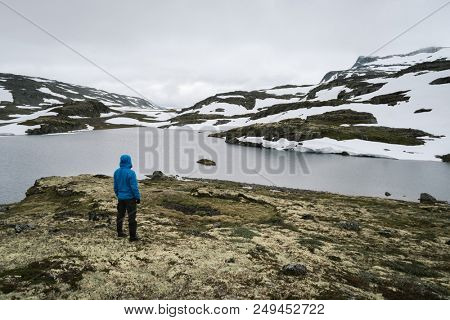 Norway, Lake Flyvotni. Near Sogn og Fjordane County Road. Norwegian Tourist Route Aurlandsfjellet runs from Aurlandsvangen to Laerdalsoyri. Traveler looks at the harsh northern nature