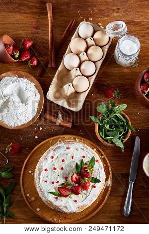 Top View Raw Ingredients For Cooking Strawberry Pie Or Cake On Wooden Table: Eggs, Flour, Sugar And 