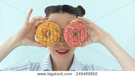 Funny Portrait Of Young Attractive Brunette On Bright Turquoise Backgroung Is Taking Two Round Donut