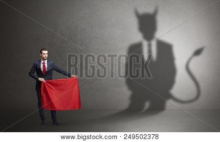 Businessman standing with red cloth in his hand and devil shadow on the background