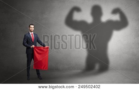 Businessman standing with red cloth on his hand and strong hero shadow on the background