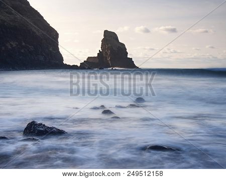 Sharp Silhouette Of A Cliff Against The Background Of Sunset. Sea Waves Break On The Rocks. Talisker