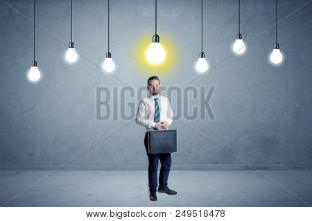 Handsome businessman in an empty space with bulbs above and uninspired face