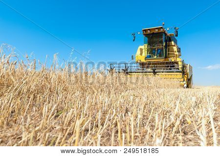 Harvester In The Foreground On Rustic Background Working In The Field