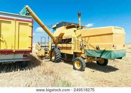Harvester In The Foreground On Rustic Background Working In The Field